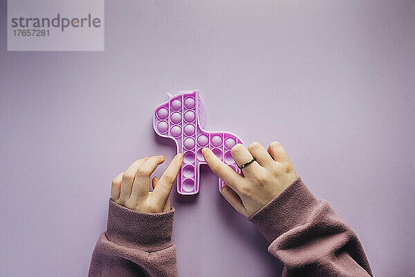 Draufsicht auf ein Mädchen  das mit einem lila Zappelspielzeug spielt