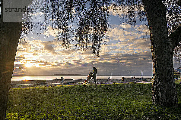 Hündin geht bei Sonnenuntergang mit ihrem Hund im Park spazieren