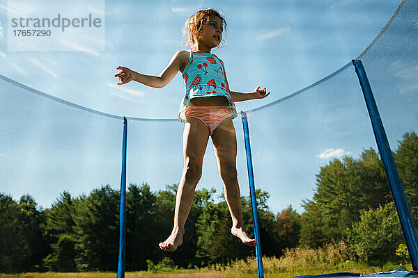 Junges Mädchen springt auf Trampolin in der Luft