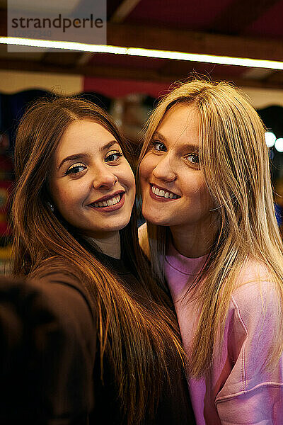 Zwei junge Frauen lächeln und machen nachts ein Selfie
