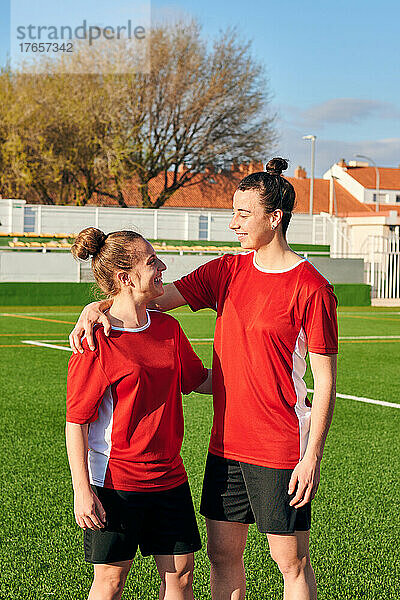 Zwei Fußballspielerinnen umarmen sich und schauen sich an