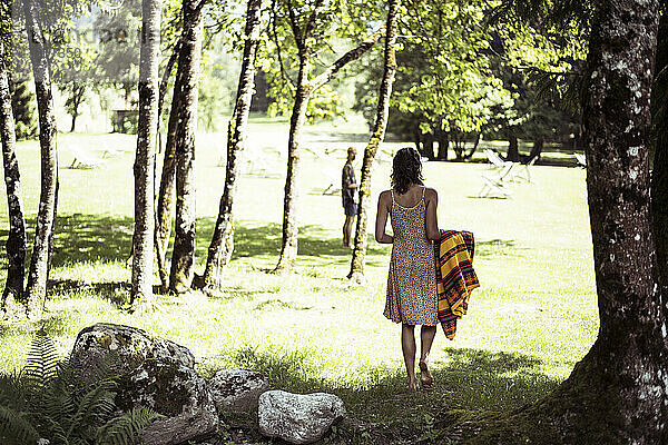 Frau im Sommerkleid bereitet Picknick im Graspark in den französischen Alpen vor
