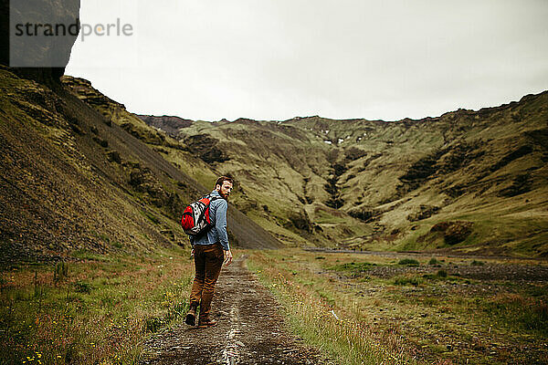 Ein Mann wandert in einem grünen Tal in Island