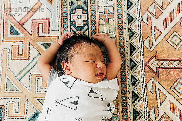Porträt eines neugeborenen Mannes  der mit über dem Kopf ausgestreckten Armen schläft