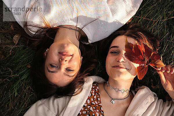 Blick von oben auf ein lesbisches Paar  das im Herbst auf Gras liegt