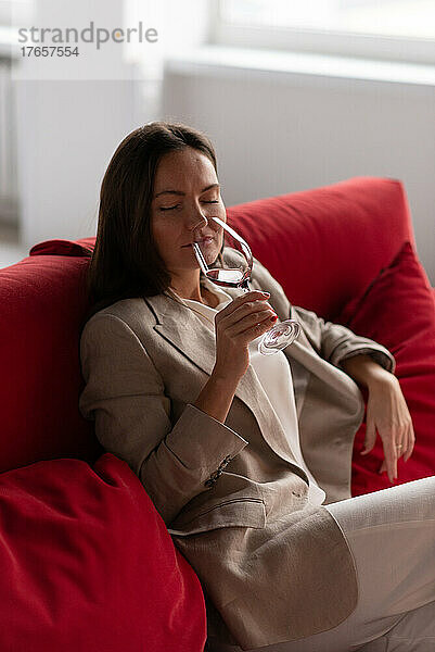 Schöne brünette Frau riecht Wein aus Glas