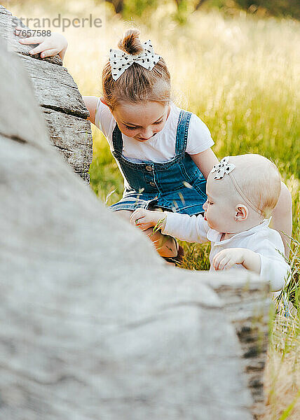 Baby und Schwester spielen zusammen im Gras