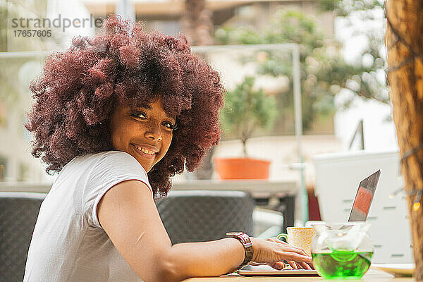 Junge Afro-Frau in einem Café  die online arbeitet