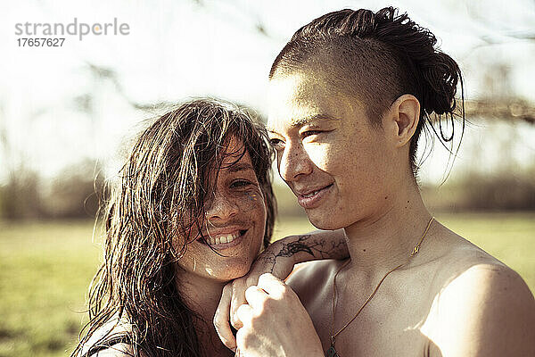Lächelndes queeres Paar im sonnigen natürlichen Nachmittagslicht