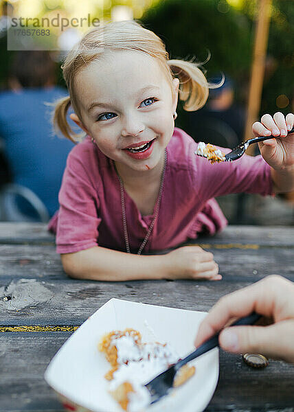 Junges Mädchen teilt sich eine Leckerei an einem Picknicktisch