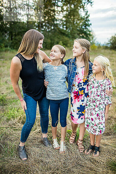 Lächelnde Mutter  die ihre drei süßen Töchter ansieht.