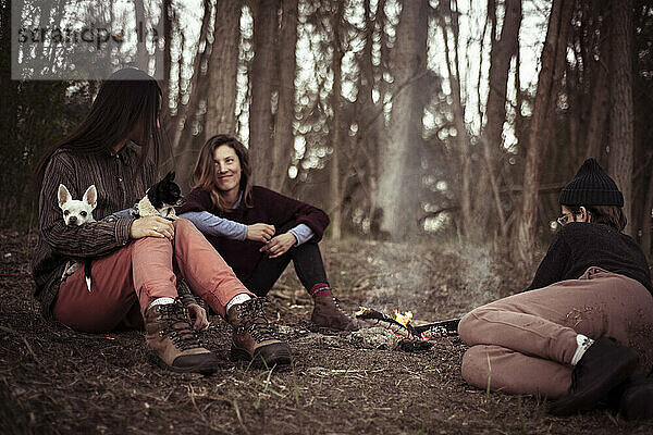 Natürlich aussehende alternative Freunde entspannen sich in der Natur am Feuer