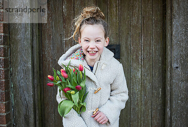 Lächelndes Mädchen  das Blumen hält  während es draußen geht