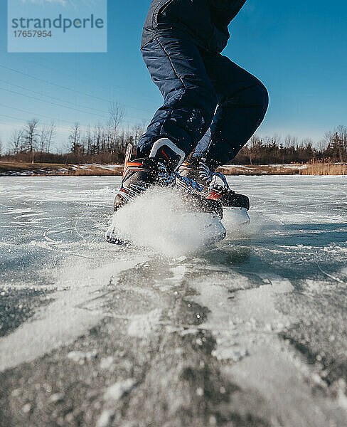 Nahaufnahme von Eishockeyschlittschuhen  die draußen auf dem Eis anhalten.
