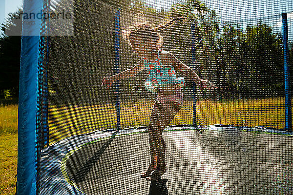 Junges Mädchen mit Zöpfen springt auf Trampolin