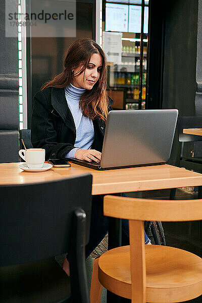 Frau arbeitet aus der Ferne mit ihrem Laptop in einem Café