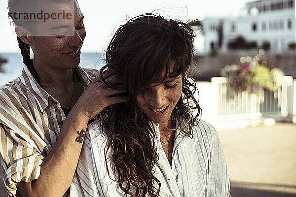 Glückliches queeres weibliches Paar lächelt liebevoll am Mittelmeer