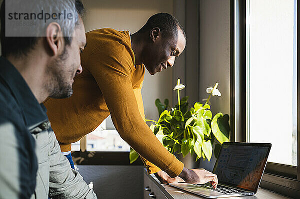 Zwei Männer entspannten sich bei der Arbeit in einem Büro mit Laptop.