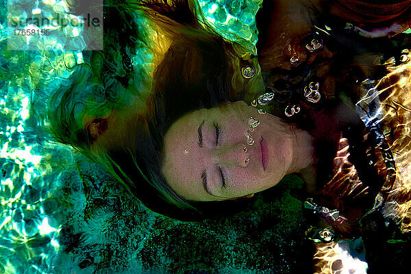 wunderschönes Porträt eines Mädchens unter Wasser mit Sonnenlicht