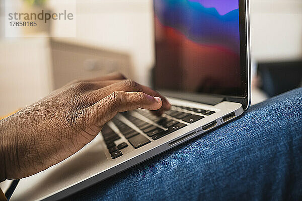 Nahaufnahme der Hände eines schwarzen Mannes  der in einem Büro auf dem Laptop tippt.