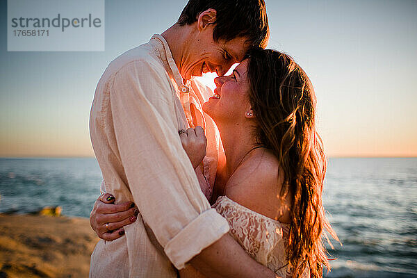Mann und Frau kuscheln bei Sonnenuntergang am Strand von San Diego
