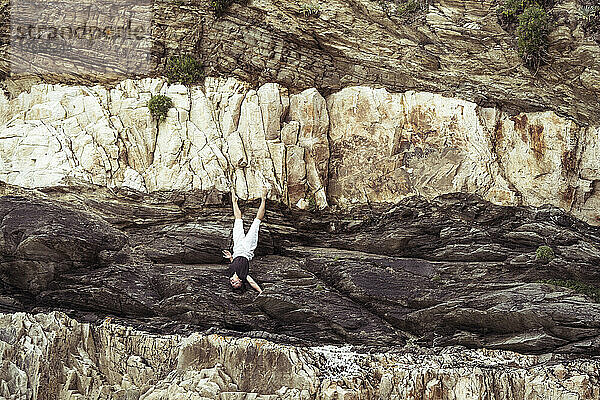 Athletischer Tänzer auf Felswand in Umkehrung
