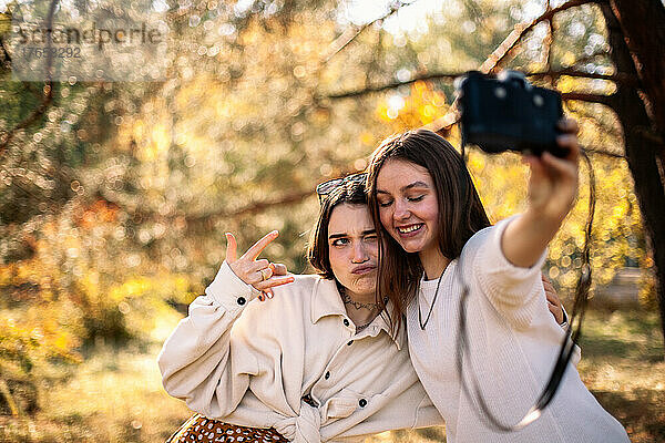 Glückliche Freundinnen machen im Herbst ein Selfie im Park