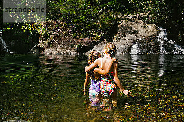 Zwei blonde Mädchen im Wasserfallpool im Sommer im Urlaub