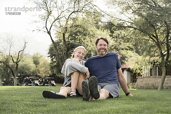 Vater und Teenager-Mädchen lächeln auf einem Rasen in Arizona