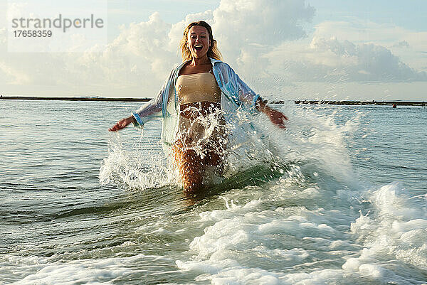Glückliches Mädchen  das auf Wellen auf der Insel Bali läuft