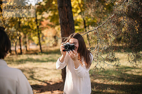 Glückliche junge Frau fotografiert Freundin im Park
