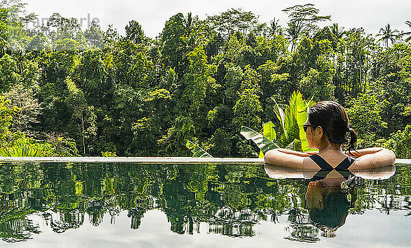 Frau genießt die Aussicht vom Infinity-Pool im Resort auf Bali