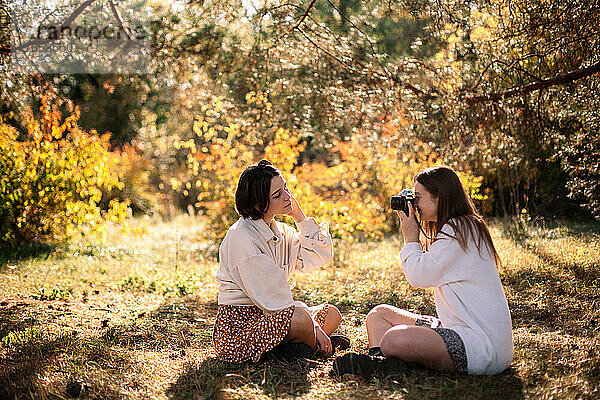 Junge Frau fotografiert Freundin im Park im Herbst