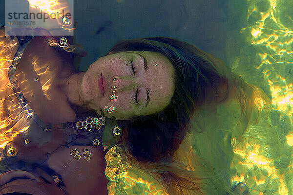 Porträt eines Mädchens  das unter Wasser Seifenblasen bläst