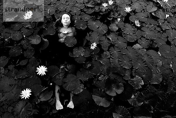 Das Mädchen liegt pflichtbewusst mit Lotusblumen im See
