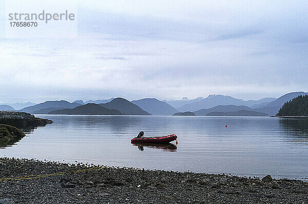 Ein leeres Boot ankerte in einer ruhigen Bucht mit Bergen im Hintergrund
