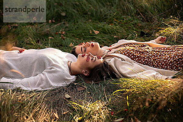 Zwei junge Frauen entspannen sich im Herbst  während sie im Gras liegen