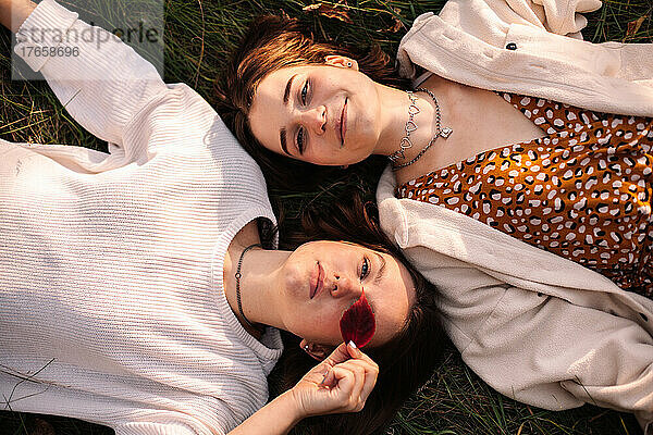 Draufsicht auf zwei junge Frauen  die im Gras liegen