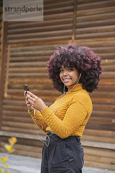 Junge Afro-Frau hört Musik auf ihrem Mobilgerät.