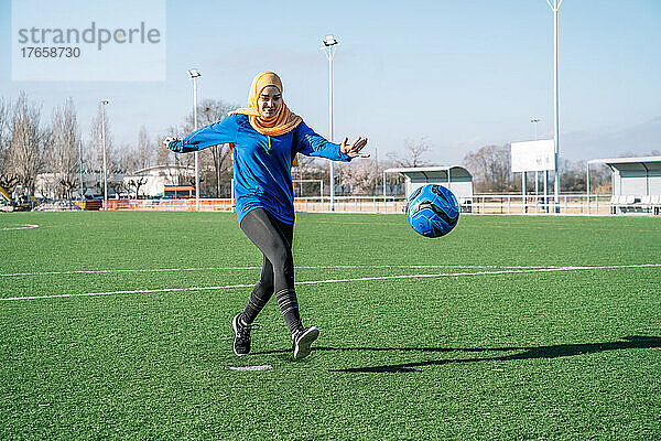 Ethnische Frau spielt Fußball auf dem Sportplatz im Stadion