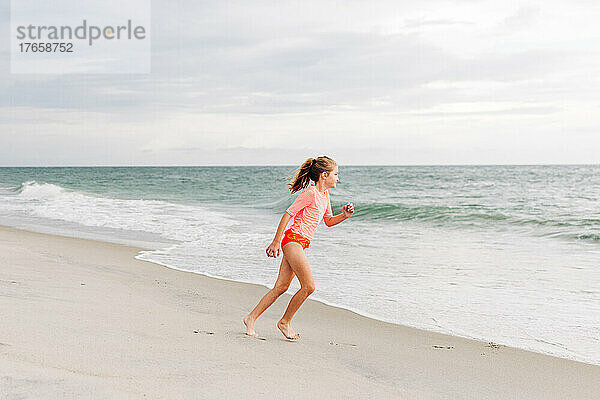 Junges Mädchen läuft im Sand in Richtung Meer
