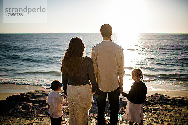 Vierköpfige Familie mit Blick auf das Meer bei Sonnenuntergang in San Diego