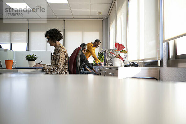 Drei Menschen unterschiedlichen Alters und unterschiedlicher ethnischer Zugehörigkeit arbeiten in einem Büro.