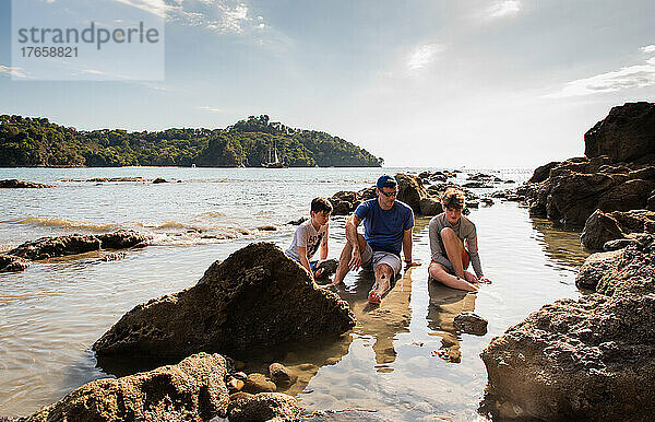 Vater und Söhne spielen im Wasser am Strand im Urlaub in Costa Rica.