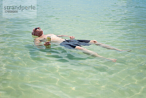Erwachsener Mann entspannt sich an einem heißen Sommertag im ruhigen Wasser des Golfs