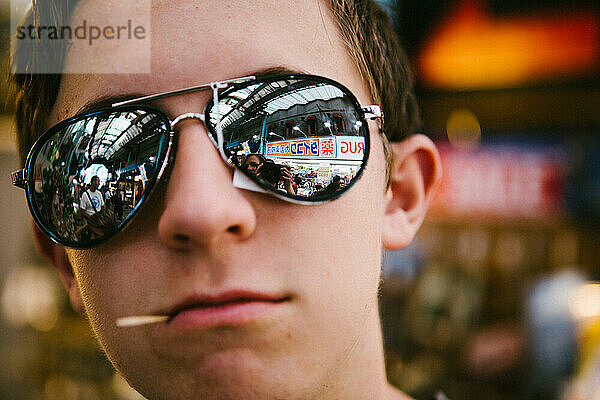 Weißer Teenager im asiatischen Einkaufsmarkt mit Sonnenbrille