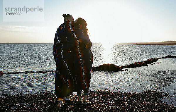 Lesbisches Paar am Strand  eingehüllt in eine Decke der amerikanischen Ureinwohner