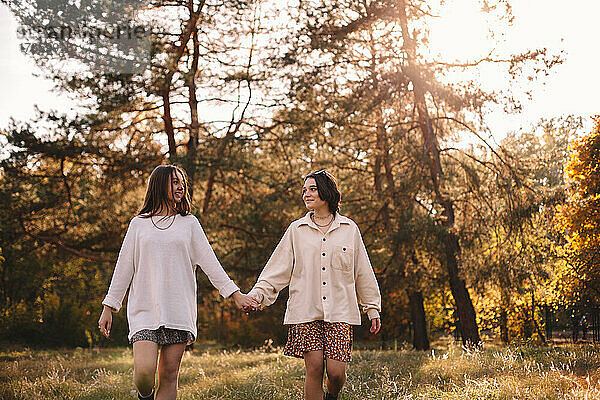 Glückliches lesbisches Paar hält Händchen beim Spaziergang im Park