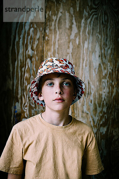 Teenager-Junge mit Schmetterlings-Eimerhut posiert für ein Solo-Porträt