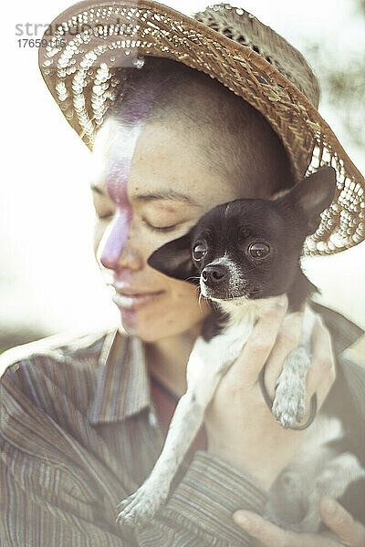 Niedlicher kleiner Chihuahua-Hund umarmt alternative Person mit Hut und Gesichtsbemalung